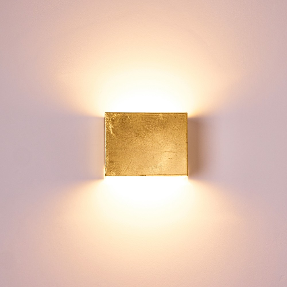 Ein goldener Würfel leuchtet an einer Wand und wirft Licht nach oben und unten.