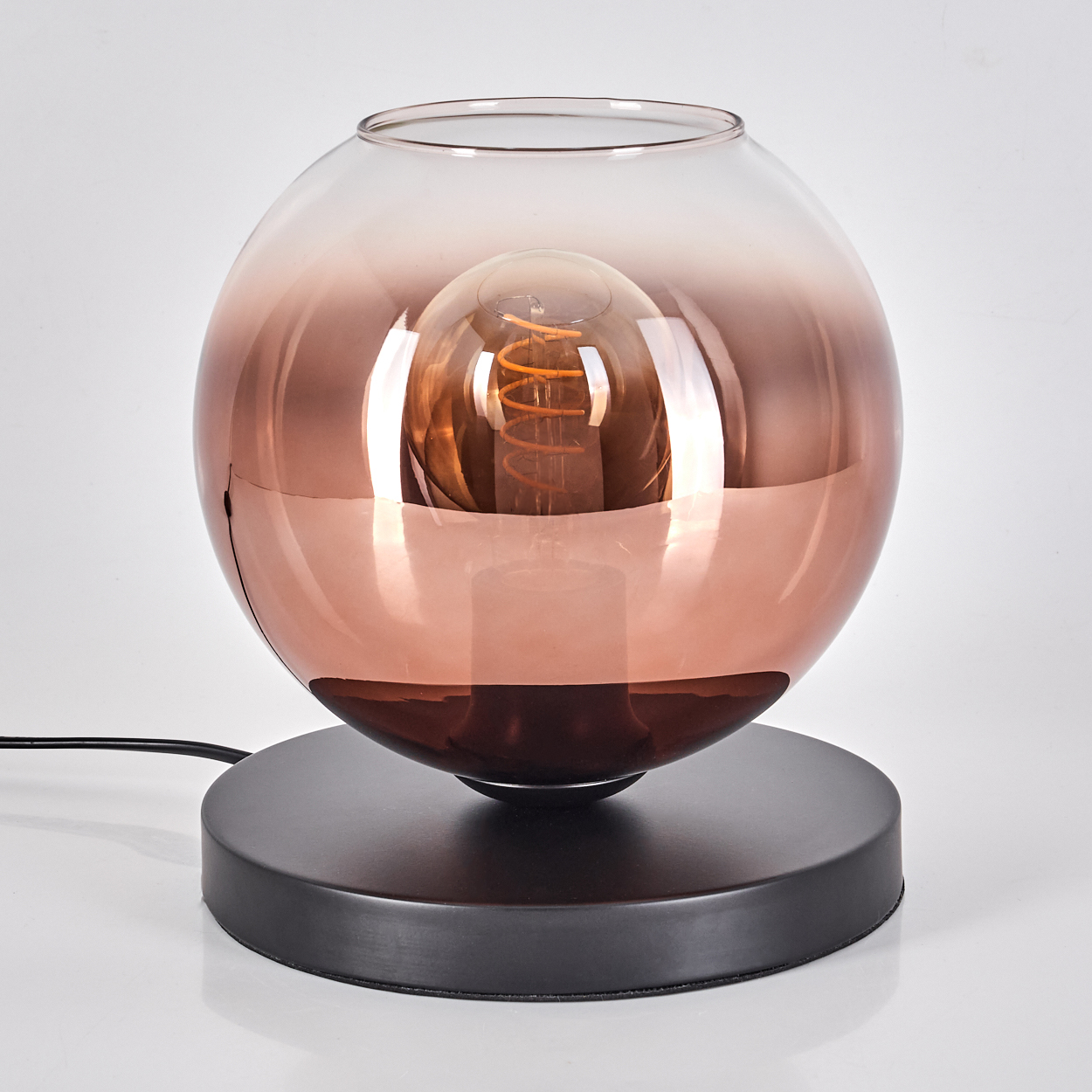 Eine kugelförmige Lampe mit kupferfarbenem Farbverlauf und sichtbarer Glühbirne.
