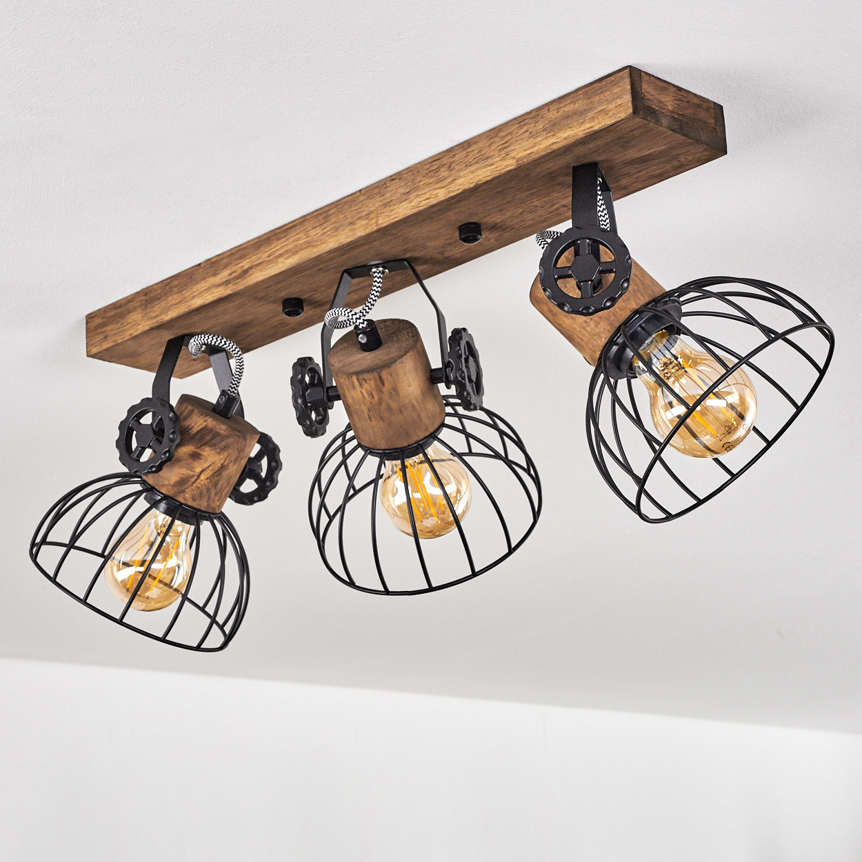 Eine Deckenleuchte aus Holz mit drei schwarzen Metallkäfiglampen und Edison-Glühbirnen.