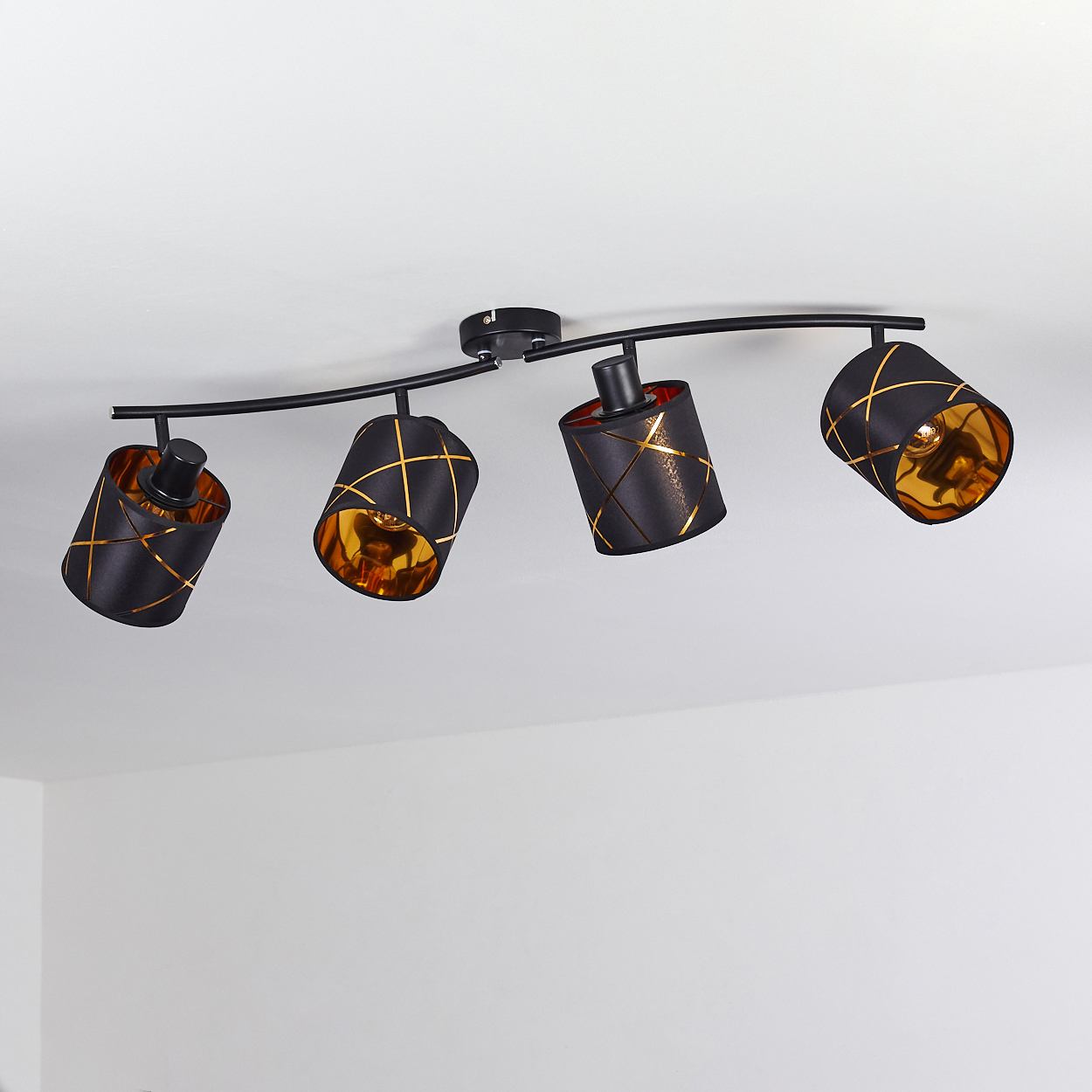 Schwarzer Deckenstrahler mit vier zylindrischen Lampenschirmen mit goldenem Muster.