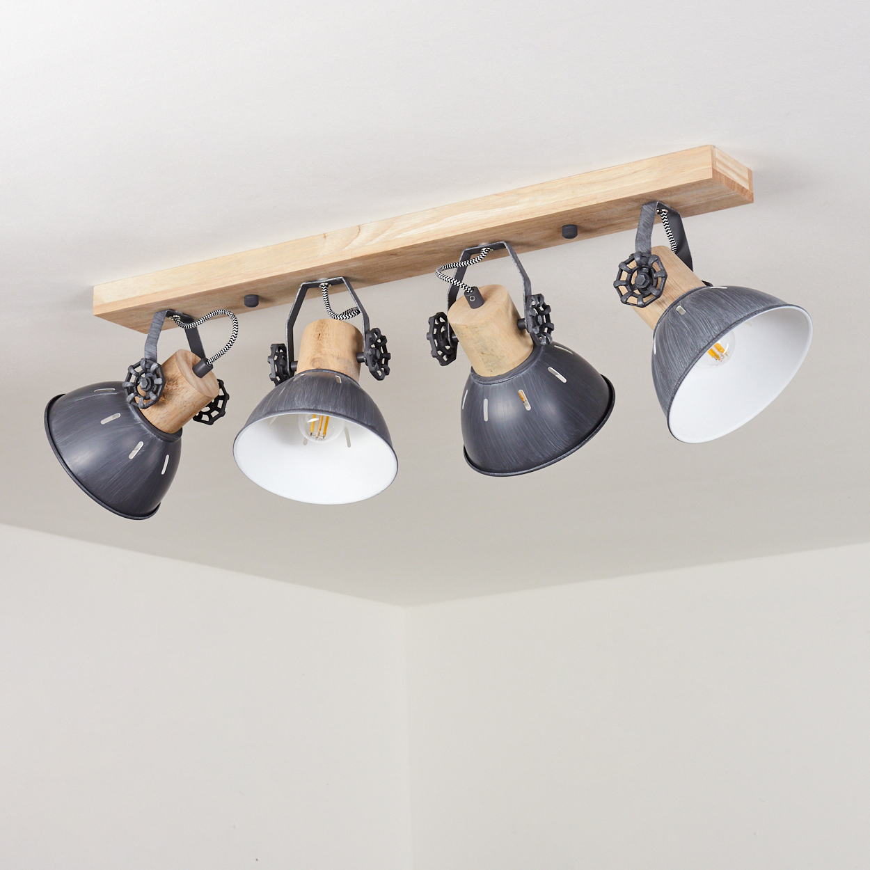 Vier graue Spots mit Holzdetails an einer Holzleiste montiert.