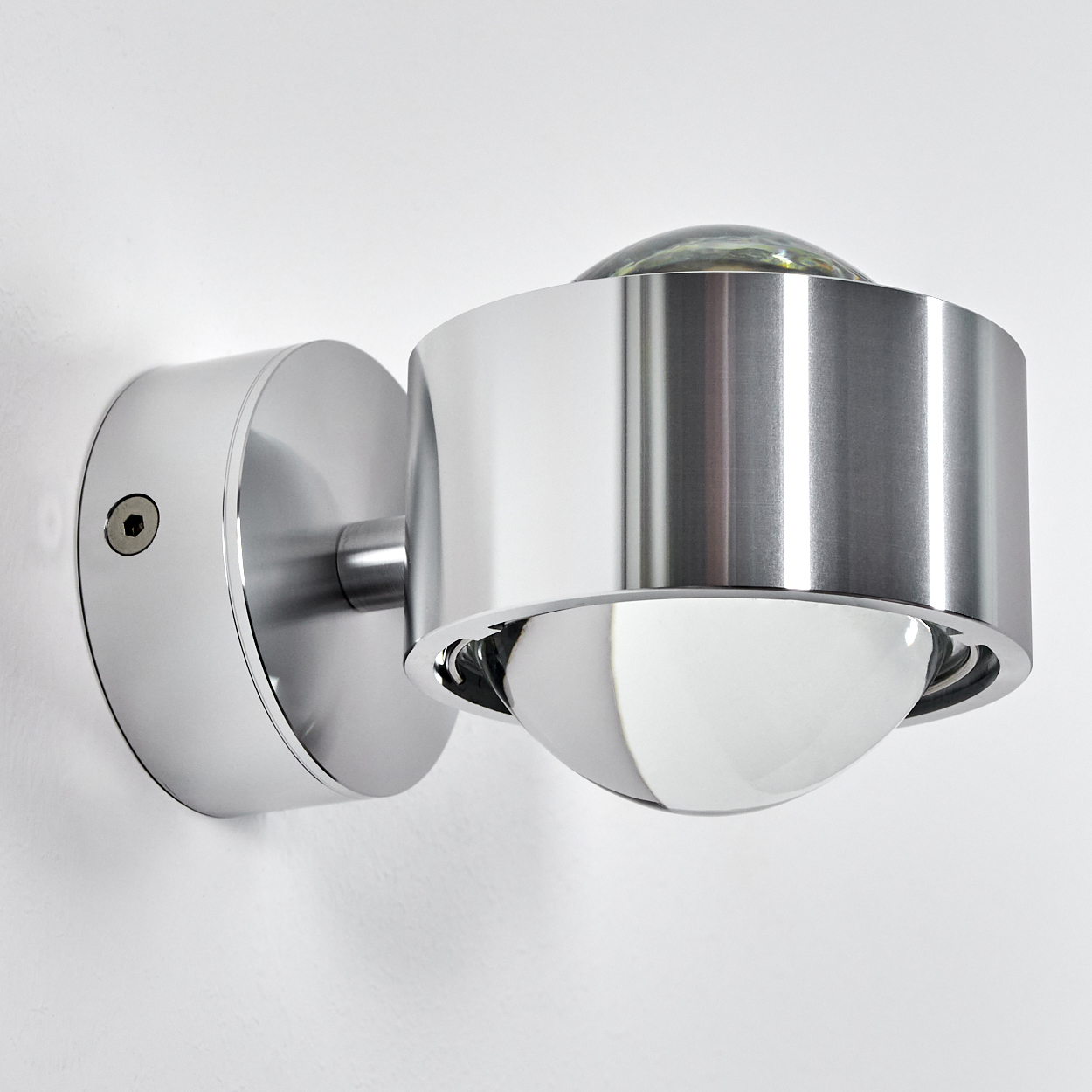 Ein moderner, runder Wandspot aus Chrom mit Glaskuppel und Metallreflektor.