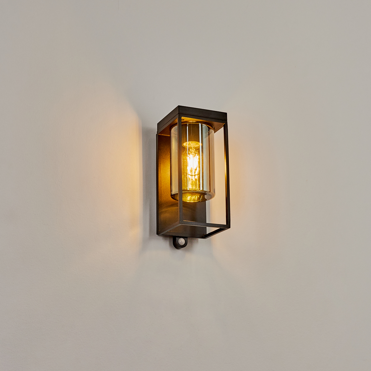 Eine moderne Wandleuchte mit schwarzem Metallrahmen und Glaskolben, der eine Glühbirne schützt.