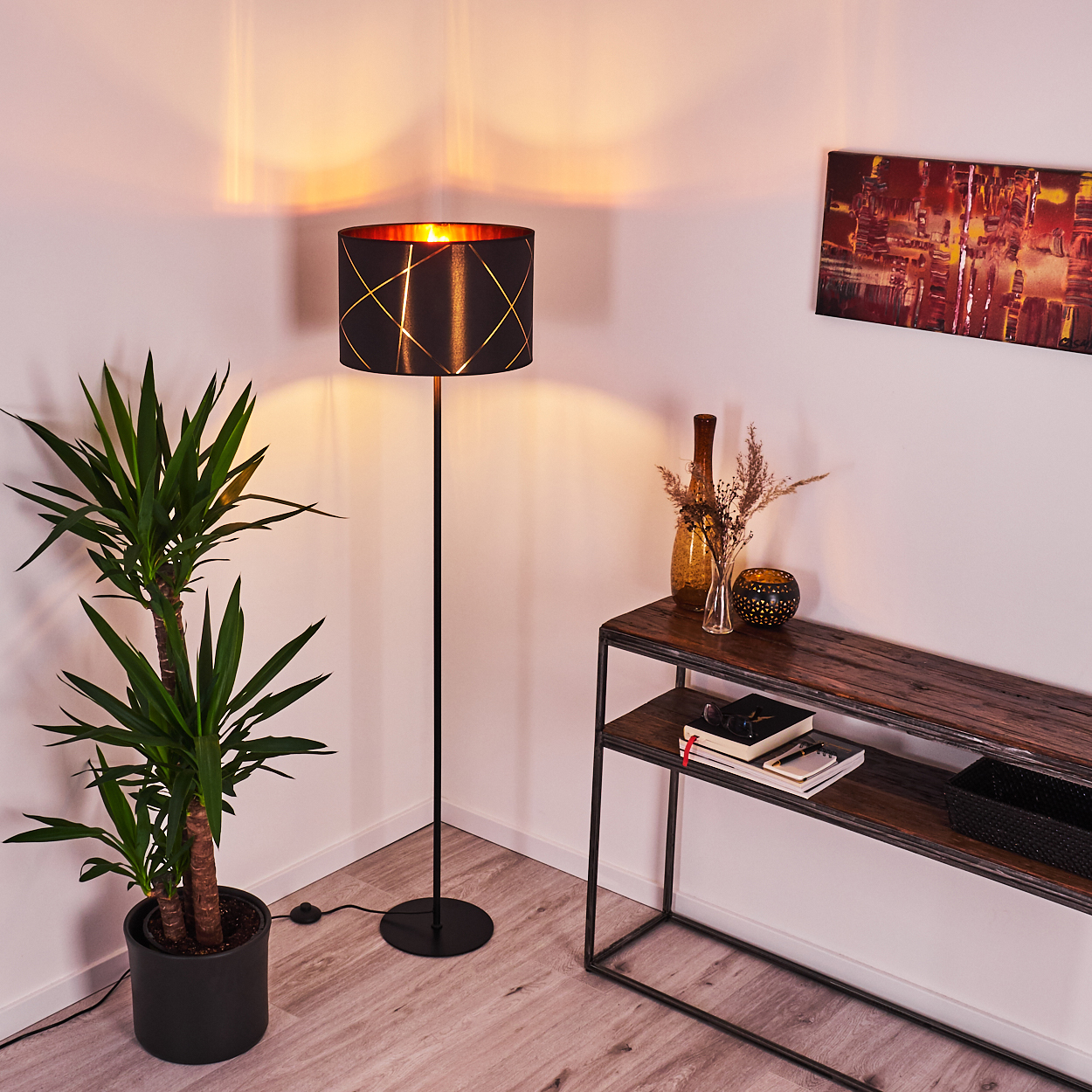 Ein Stehlampe mit schwarzem Schirm, eine Pflanze und ein Regal mit Dekoration.