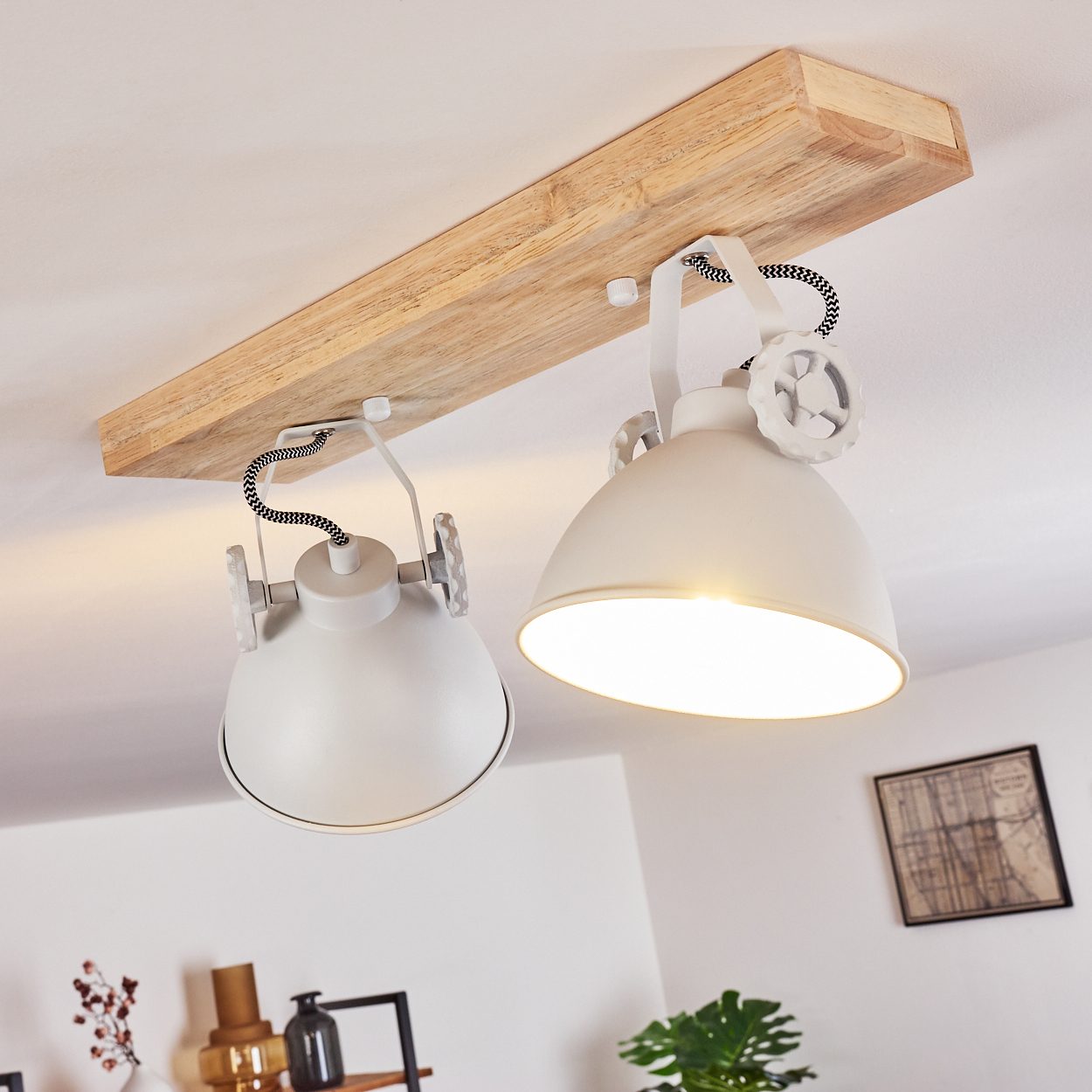 Zwei weiße Lampenschirme hängen an einem Holzbalken an der Decke.