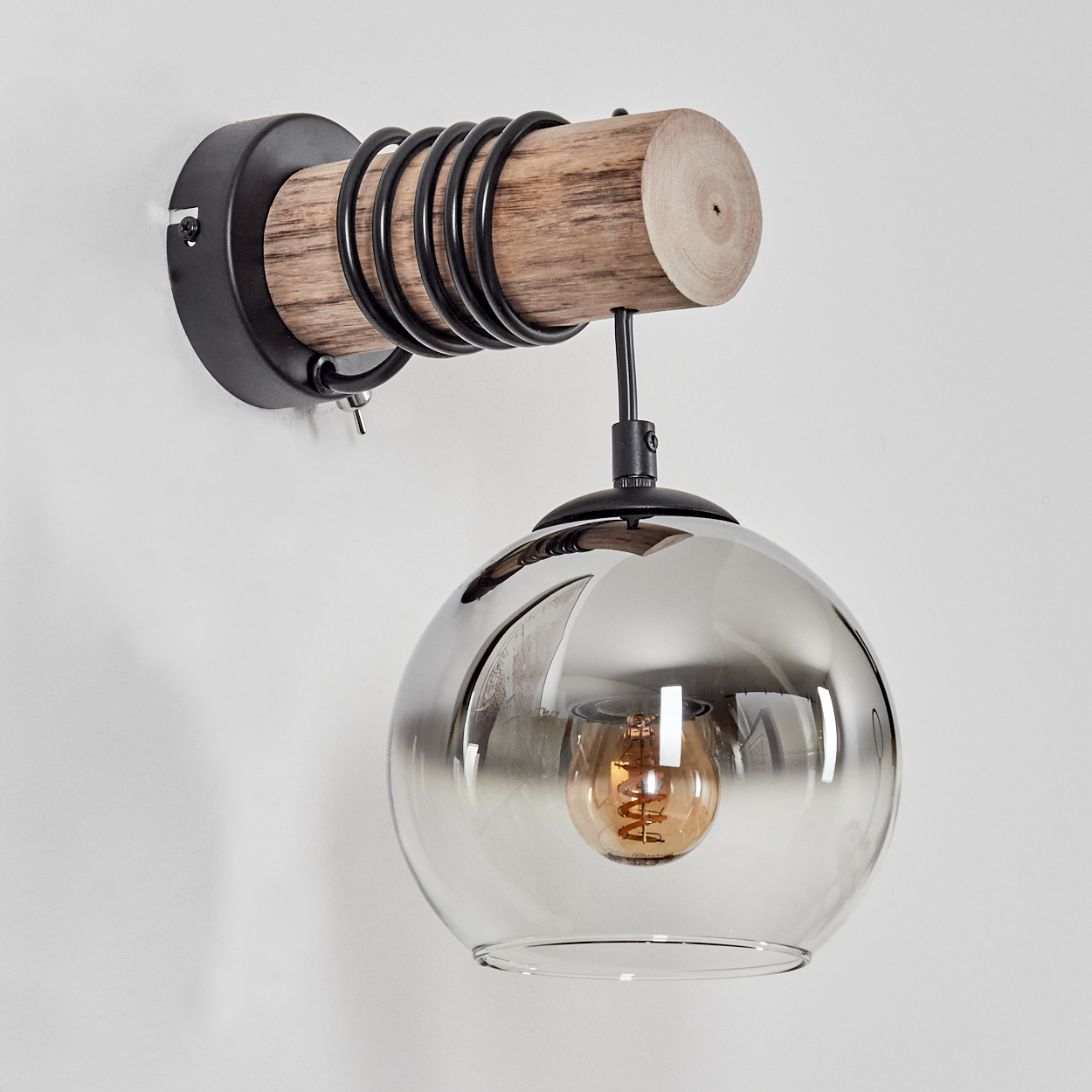 Eine Wandleuchte mit Holzstamm, Metall und einem rauchigen Glasglobus.