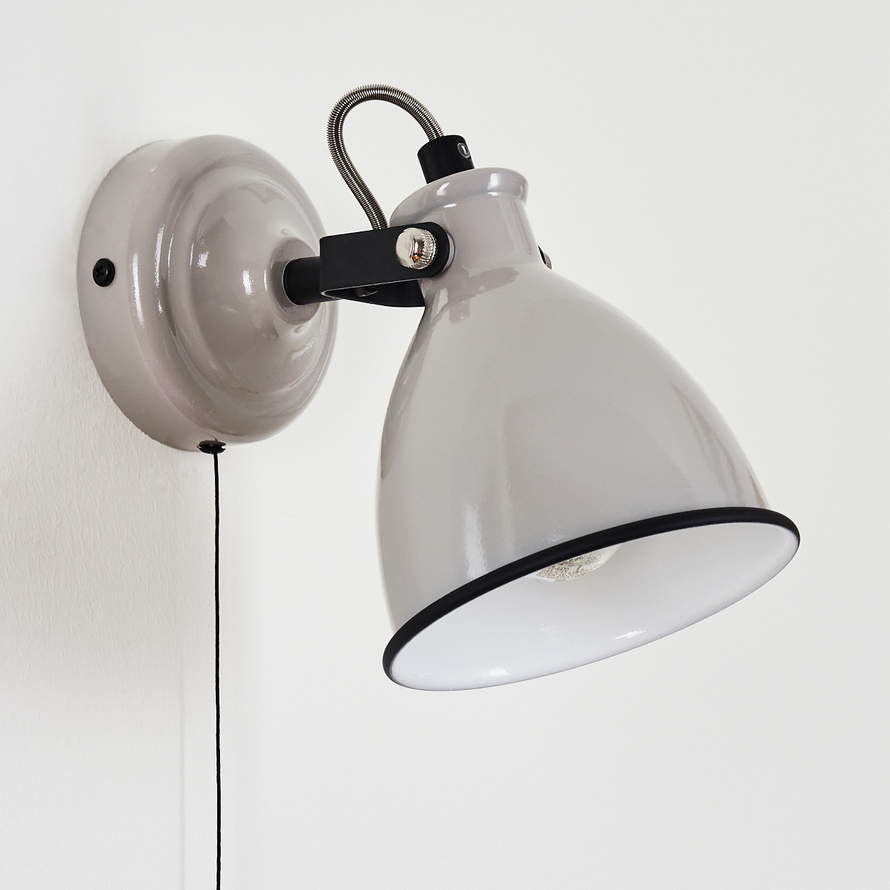Graue Wandleuchte mit schwarzem Kabel und verstellbarem Arm. Glänzende Oberfläche.