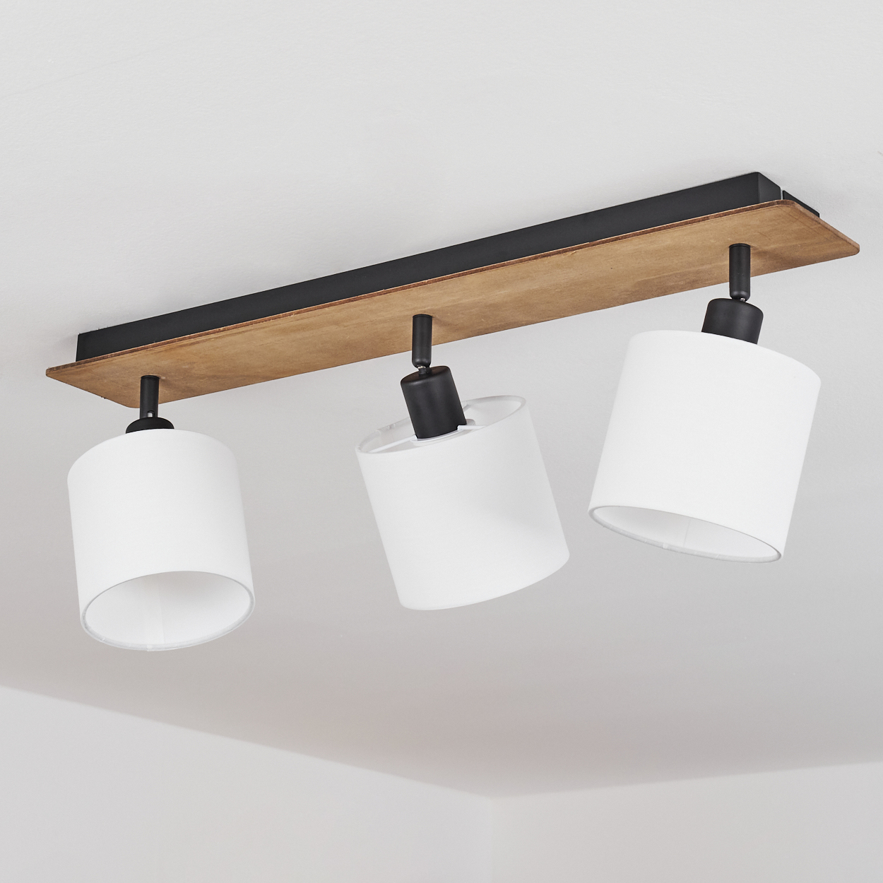 Deckenleuchte mit Holz und schwarzem Metallrahmen, drei weiße Zylinderlampenschirme.