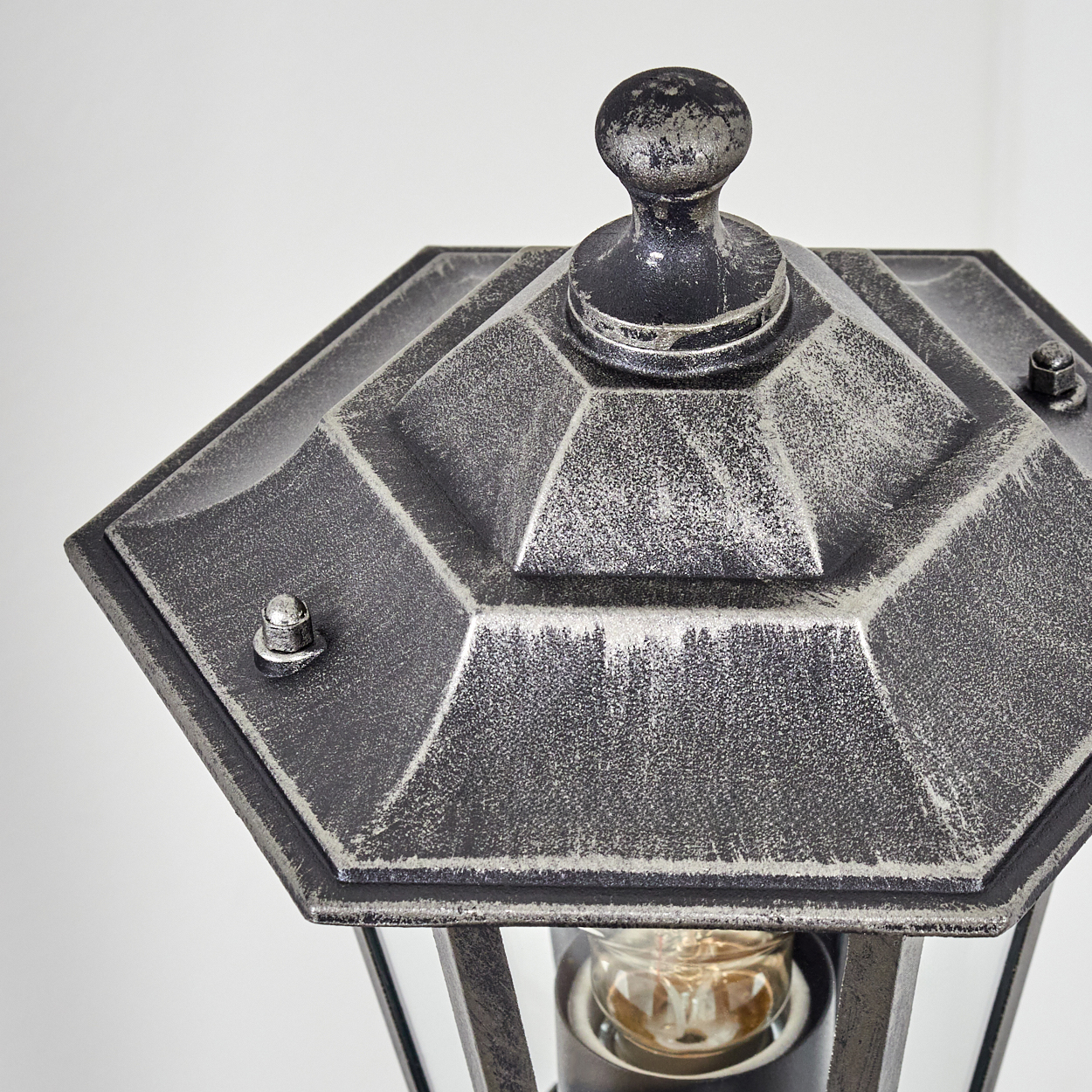 Nahaufnahme einer sechseckigen Laternenhaube aus dunklem Metall mit silbernen Akzenten.