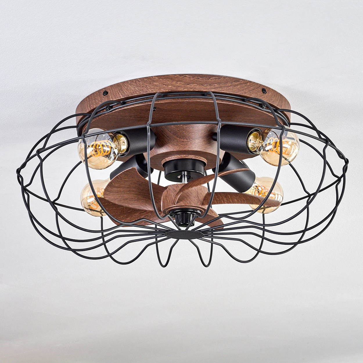 Ein rustikaler Deckenventilator mit Holzsockel, schwarzem Metallkäfig und vier Edison-Glühbirnen.