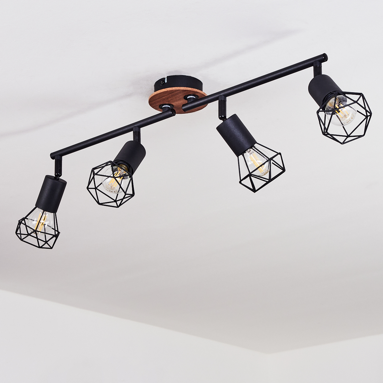 Ein schwarzer Deckenstrahler mit vier Lichtern, geometrischen Käfigen und Edison-Glühbirnen.