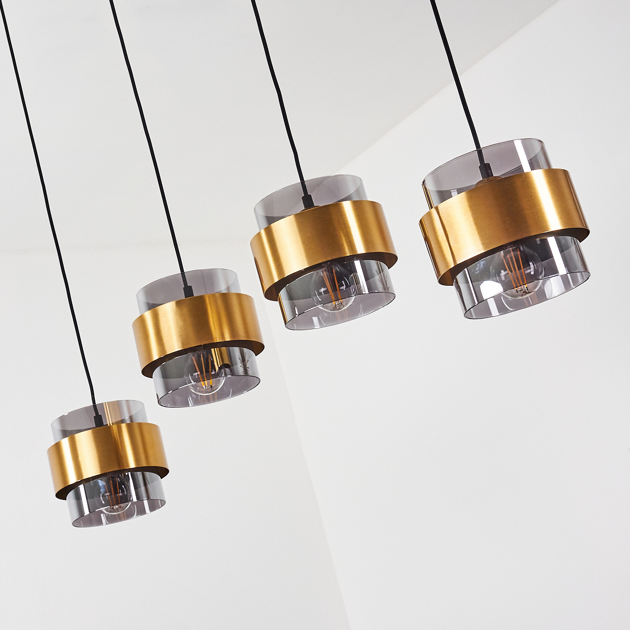 Vier Pendelleuchten mit goldenen Ringen und Rauchglaszylindern.