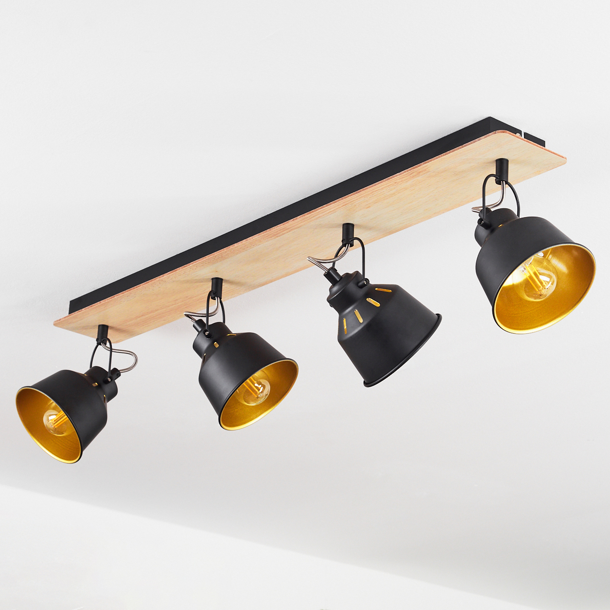Eine schwarze Deckenleuchte mit vier verstellbaren Spots auf Holzsockel.