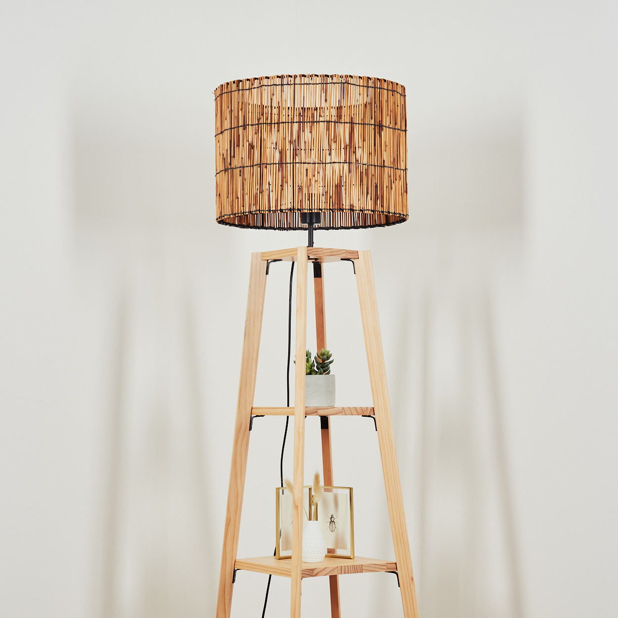 Ein Stehlampenfuß aus Holz mit einem Lampenschirm aus Bambus und zwei Regalen.