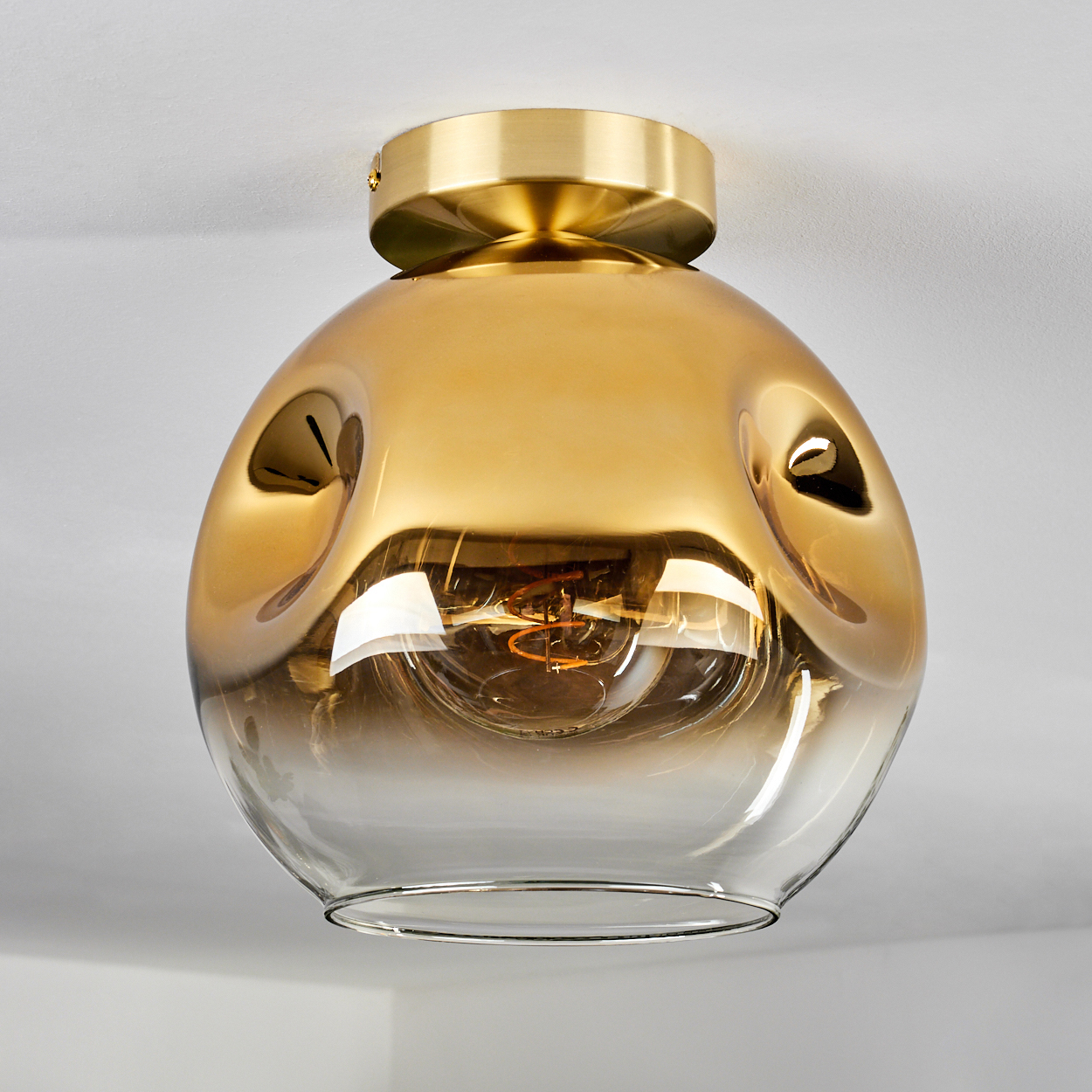 Eine goldene, kugelförmige Deckenleuchte mit sichtbarer Glühbirne.
