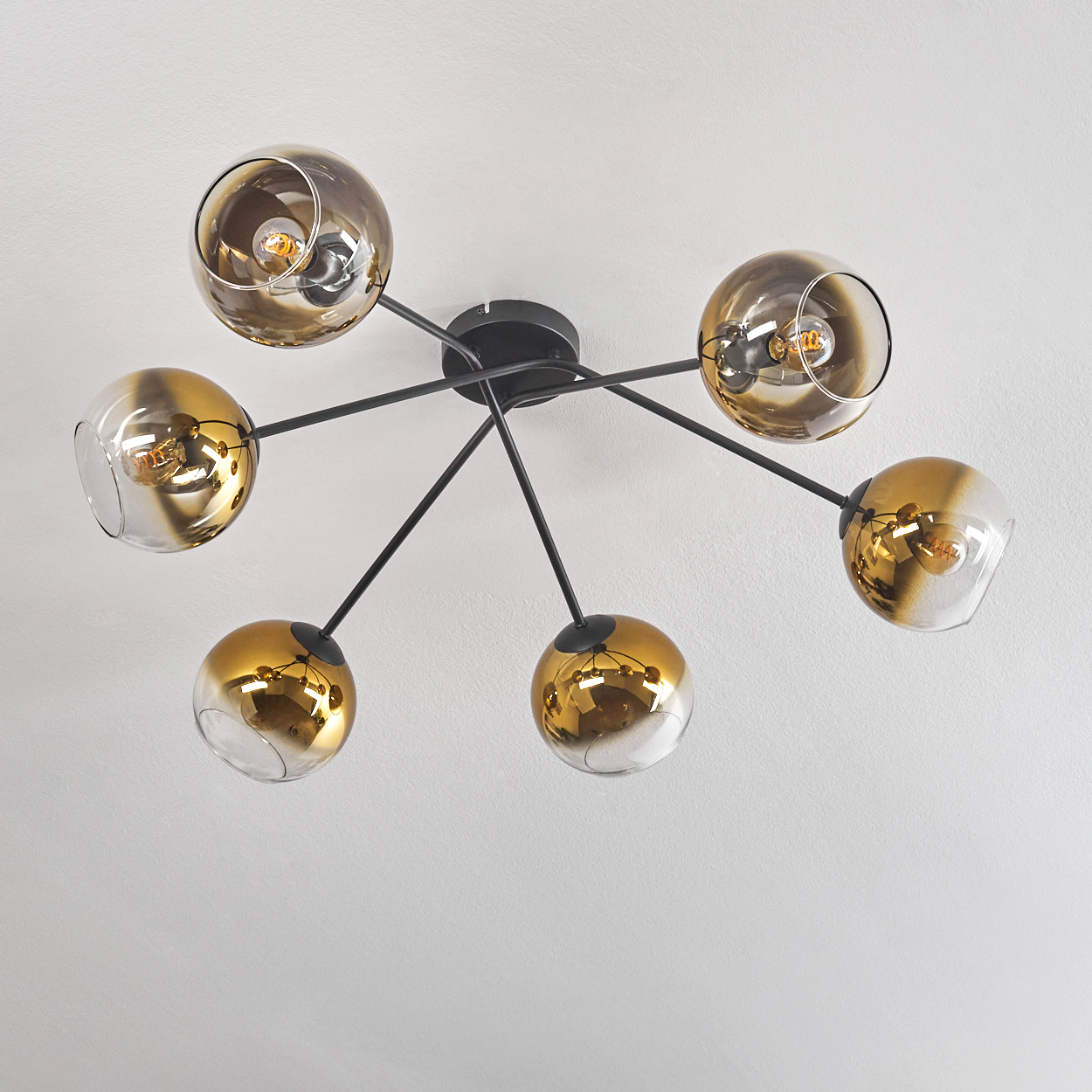 Eine moderne Deckenleuchte mit sechs Armen und Glaskugeln in Gold und Rauchglas.