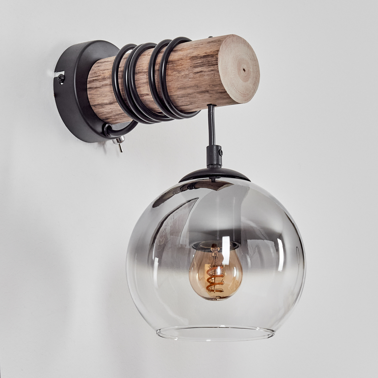 Eine Wandleuchte mit Holzbalken, schwarzen Spiralen und einem rauchigen Glaslampenschirm.