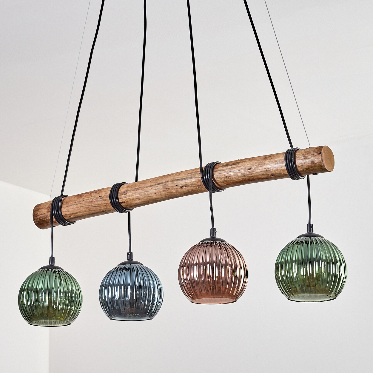 Kronleuchter mit Holzbalken und vier bunten Glaskugelleuchten an schwarzen Kabeln.