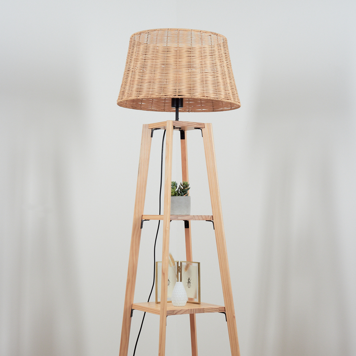 Ein Lampenständer aus Holz mit geflochtenem Lampenschirm, mit einem Topf und zwei Rahmen.