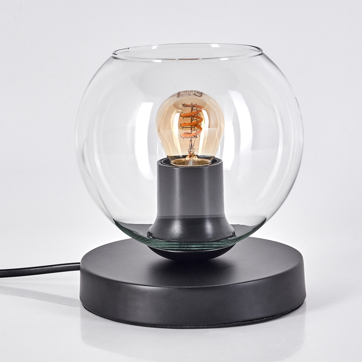 Eine schwarze Schreibtischlampe mit einer kugelförmigen Glasglocke und einer sichtbaren Glühbirne.