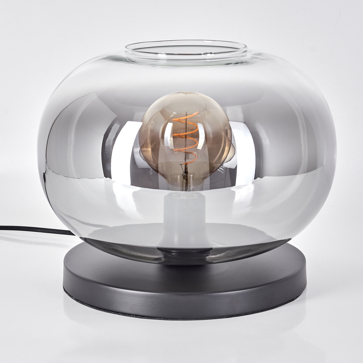 Eine Tischlampe mit einem grauen Sockel und einem runden Glasschirm.