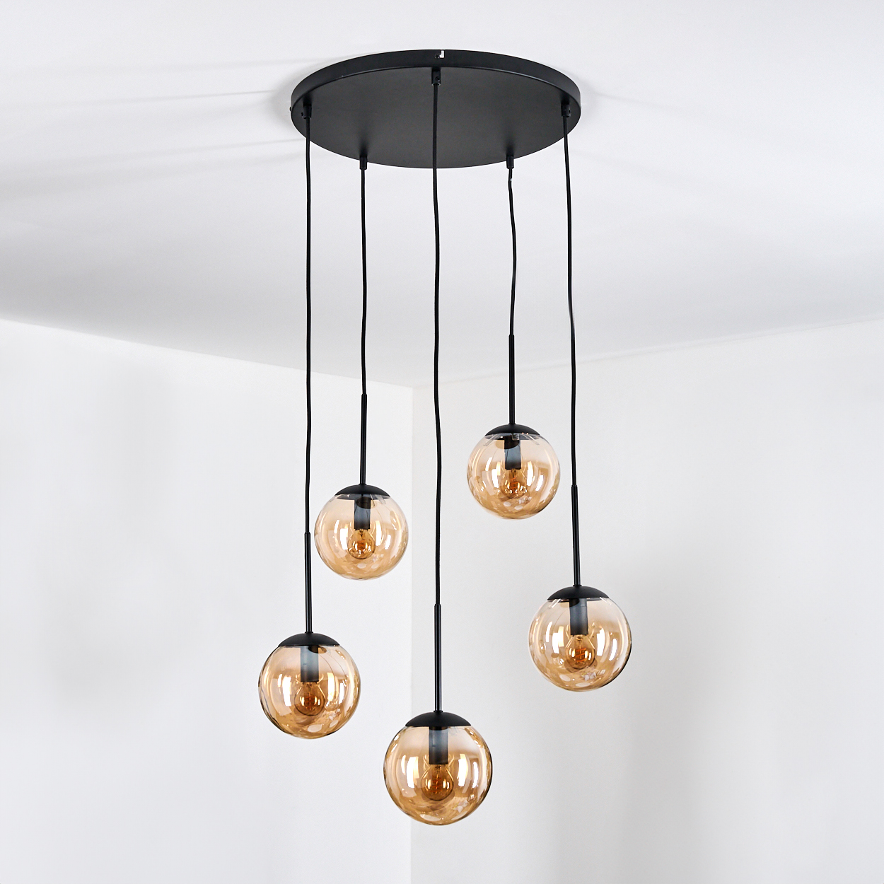 Eine schwarze Deckenlampe mit fünf bernsteinfarbenen Glaskugeln.