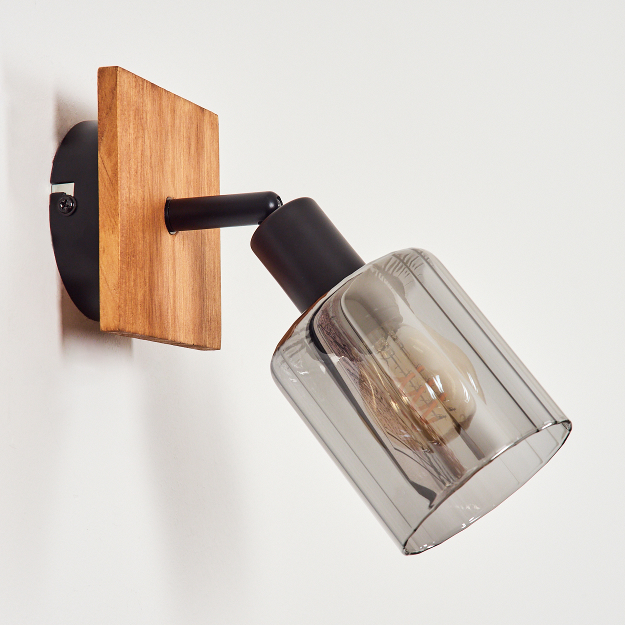 Ein schwarzer Wandspot mit Holzsockel und Rauchglas-Schirm.
