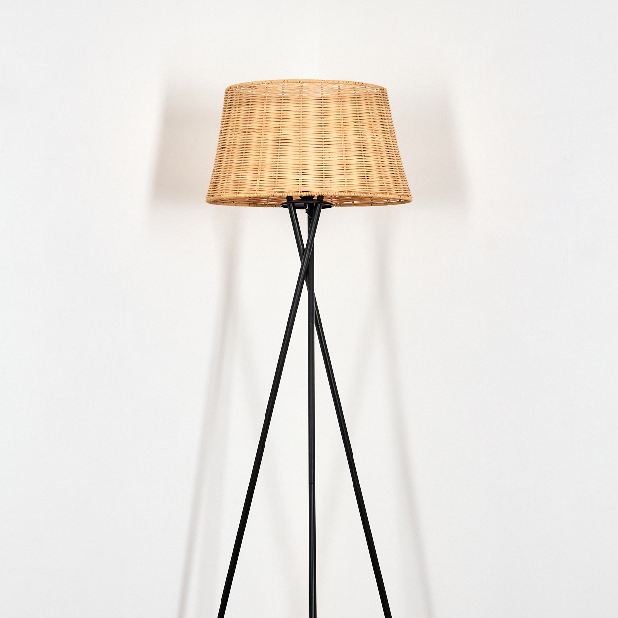 Ein Stehlampe mit einem geflochtenen Lampenschirm aus Weidengeflecht.