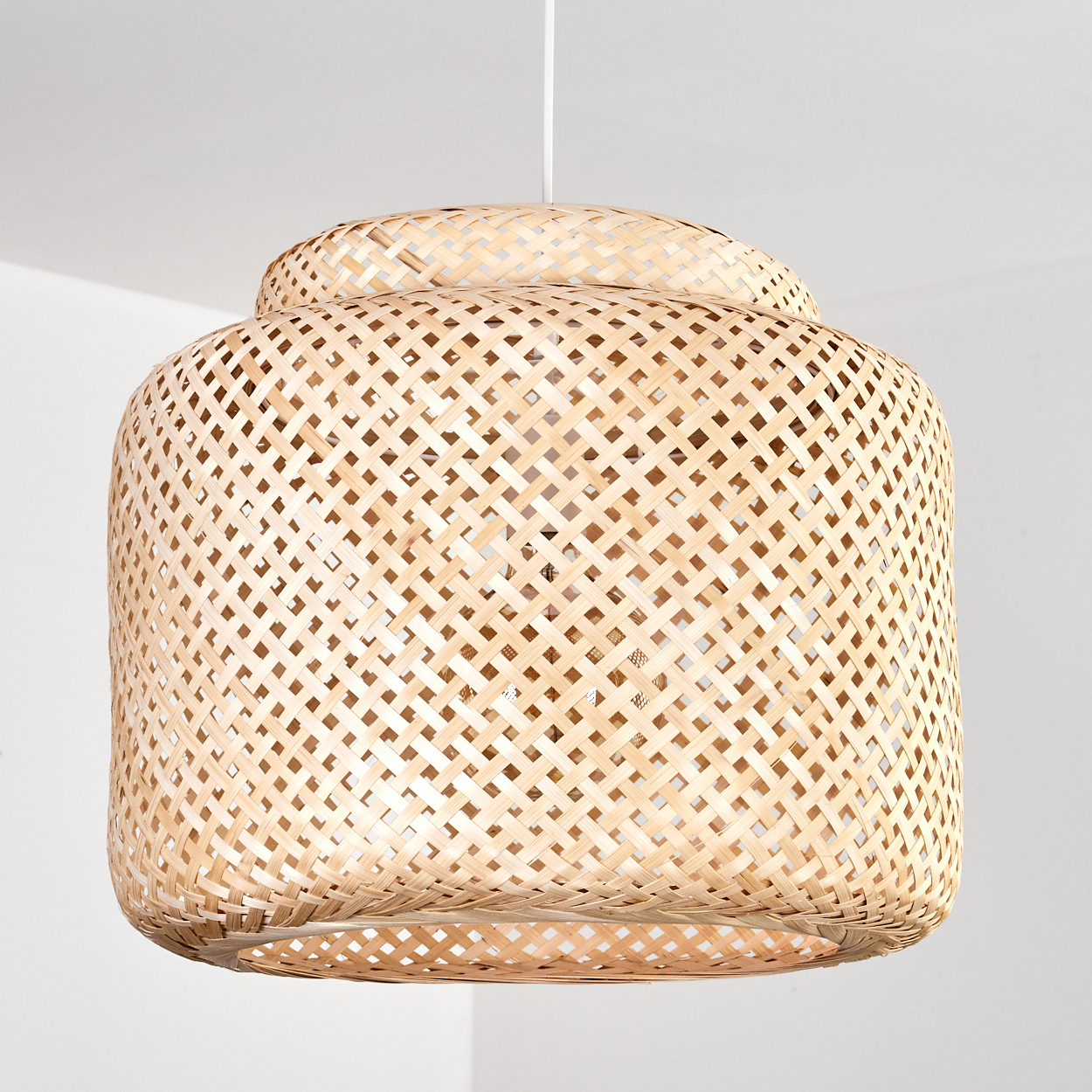 Eine hängende Lampe aus geflochtenem Bambus mit einem schichtartigen Design.