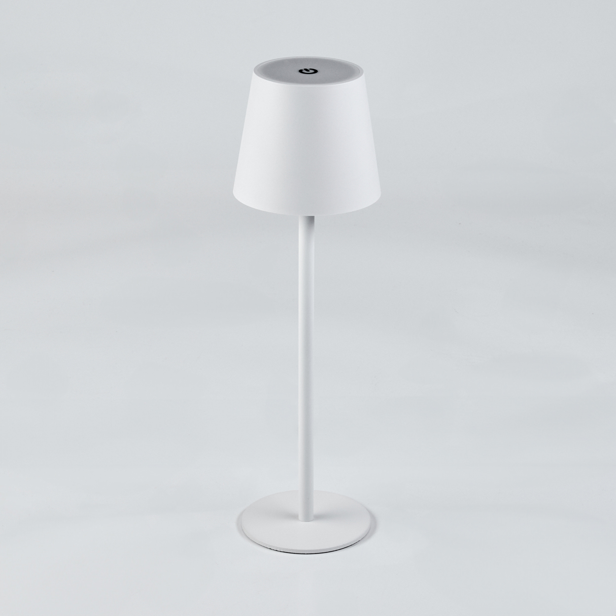 Eine weiße Nachttischlampe mit einem kegelförmigen Schirm und einem runden Fuß.