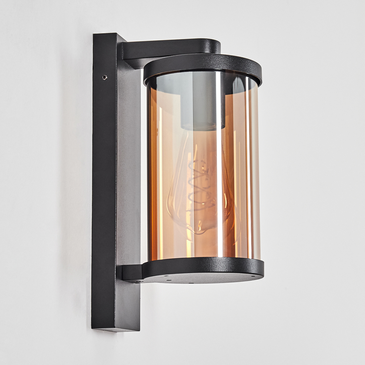 Moderne Wandleuchte mit schwarzem Gestell und bernsteinfarbenem Glaszylinder.