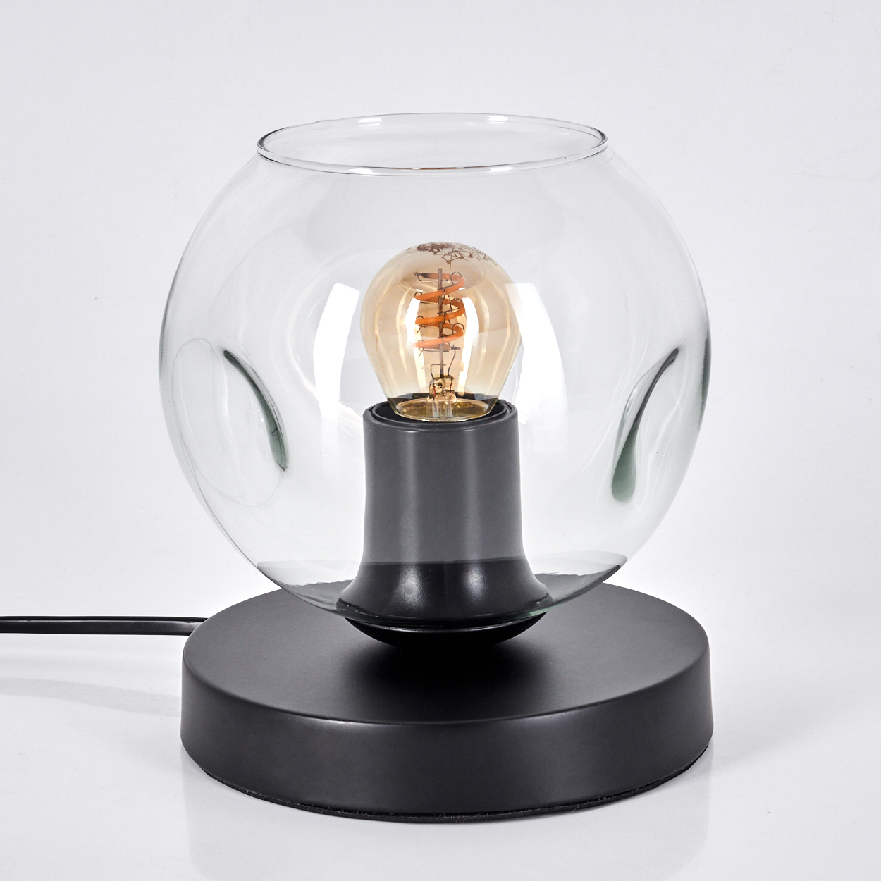 Eine moderne schwarze Tischlampe mit klarem Glaskugel-Schirm und freiliegender Edison-Glühbirne.