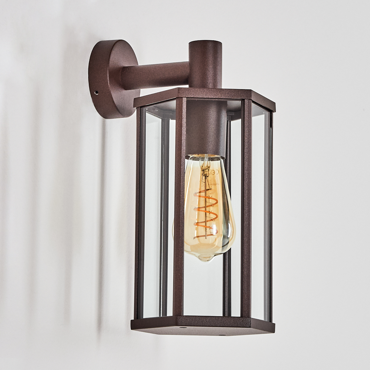 Eine braune Wandleuchte mit Glasfenstern und einer Edison-Glühbirne.