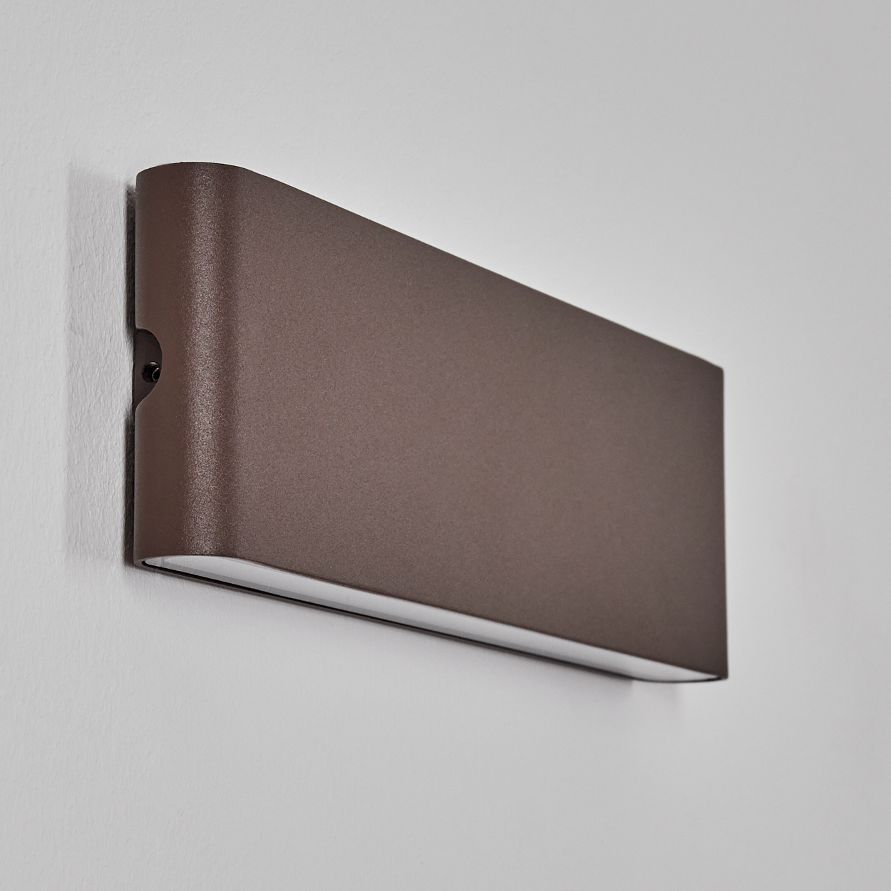 Braune Wandleuchte mit schlichtem Design an weißer Wand.