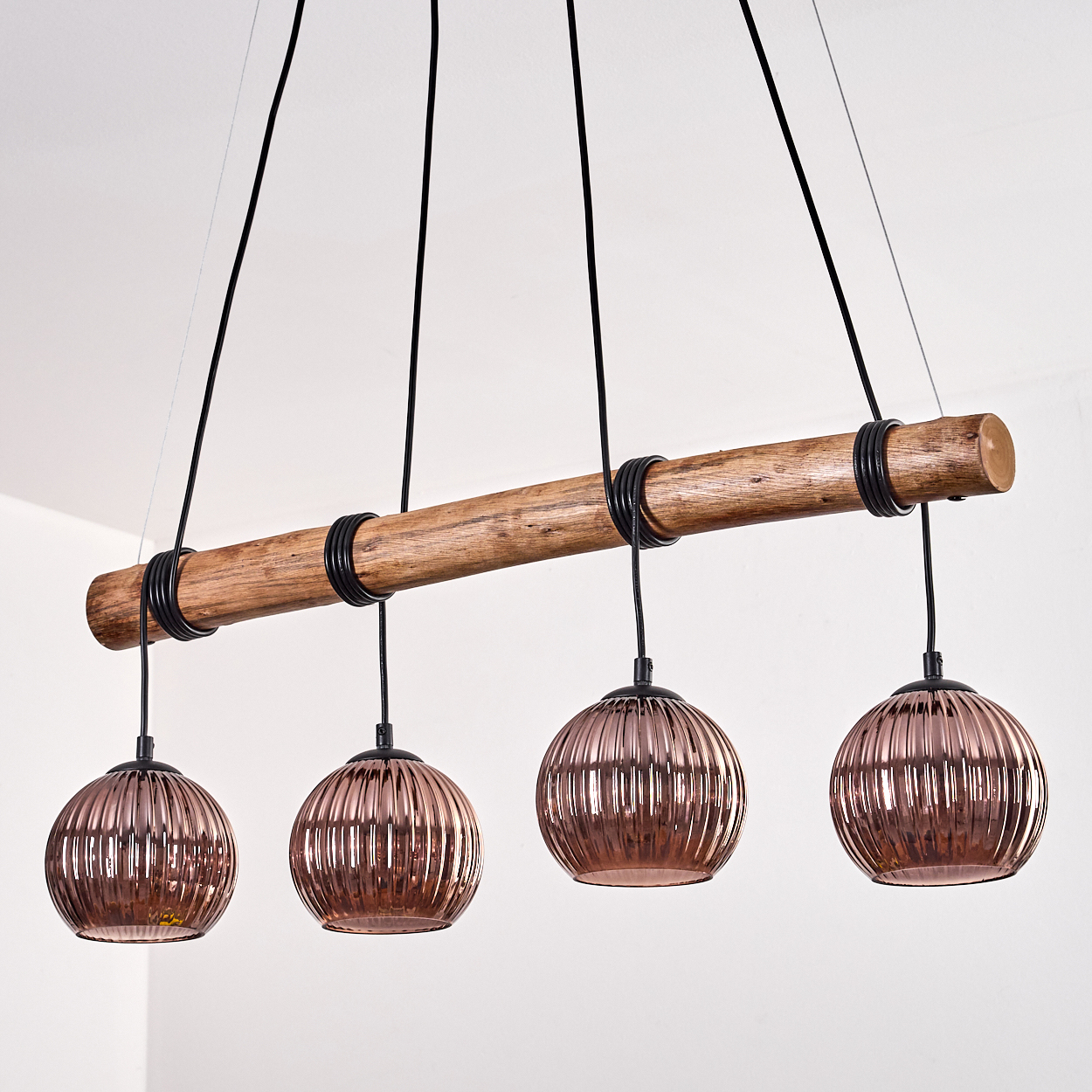Hängelampe mit Holzstamm, vier kupferfarbenen Glaskugeln und schwarzen Kabeln.