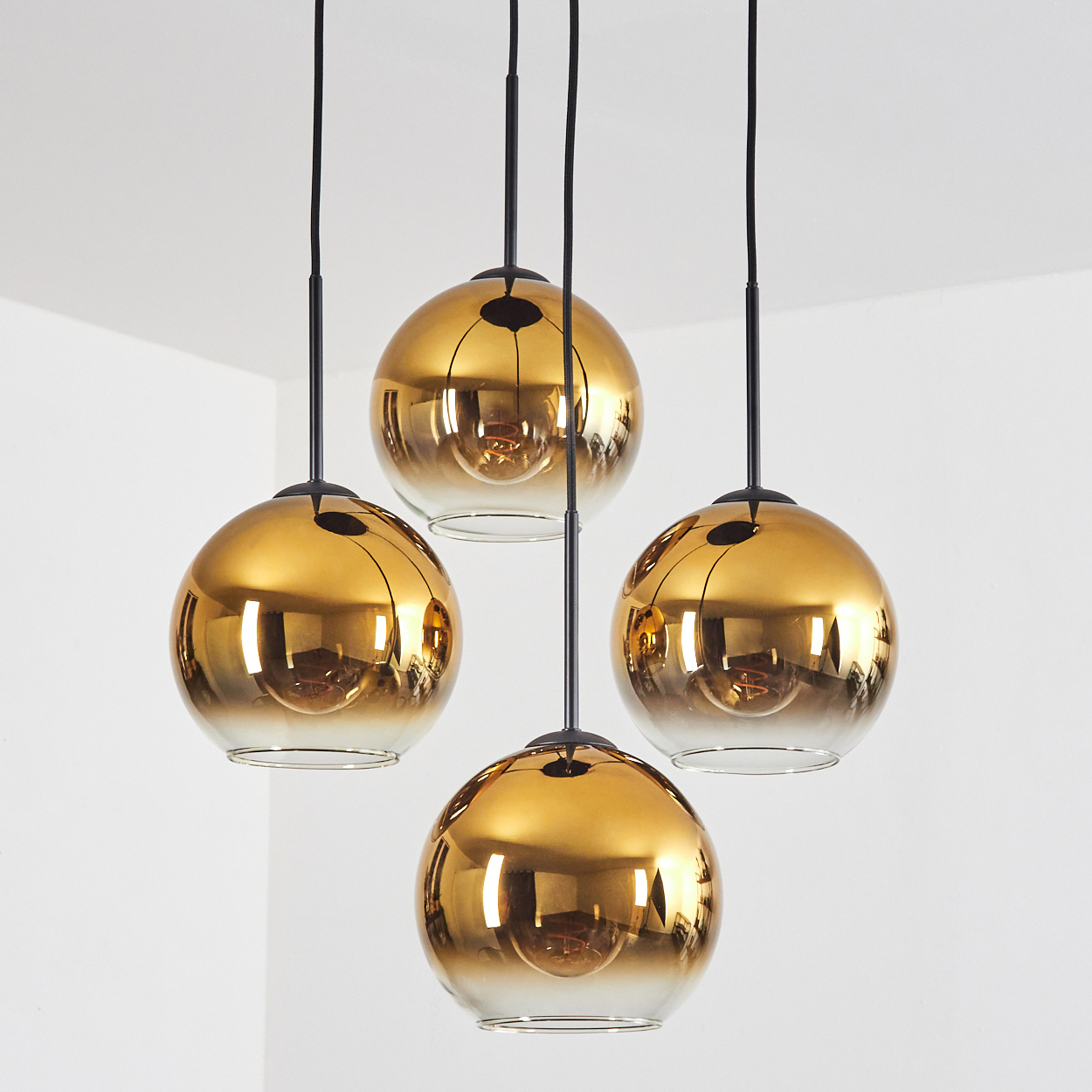 Vier goldene Pendelleuchten mit Glaskugeln hängen von der Decke.