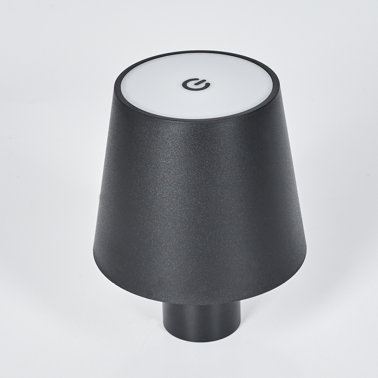 Eine schwarze Lampe mit einem weißen oberen Bereich und einem Ein-/Ausschaltsymbol.