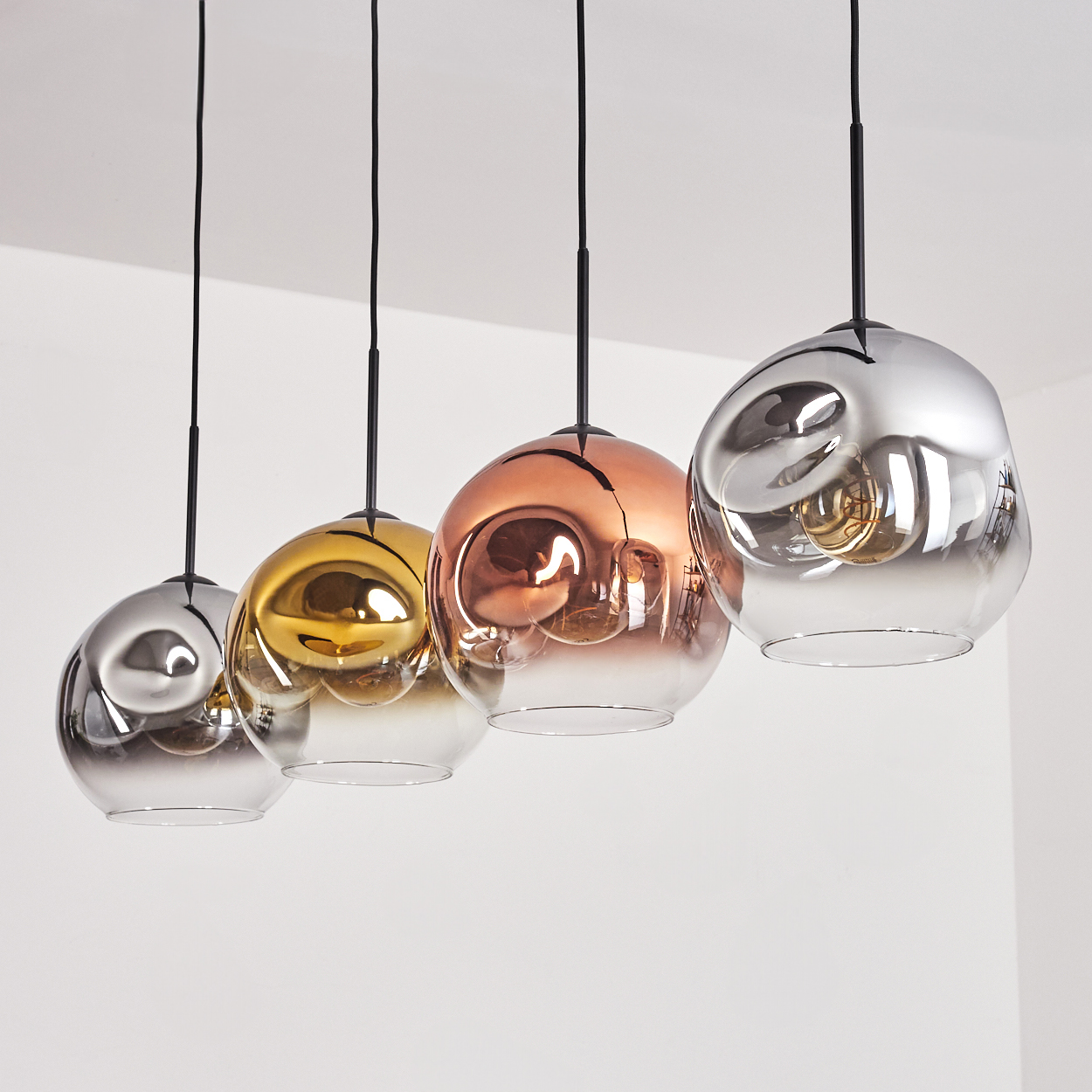 Vier Hängeleuchten mit kugelförmigen, spiegelnden Lampenschirmen in Silber, Gold und Roségold.
