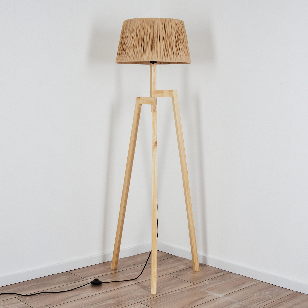 Ein Stehlampenständer aus Holz mit einem kegelförmigen Lampenschirm aus Naturfasern.