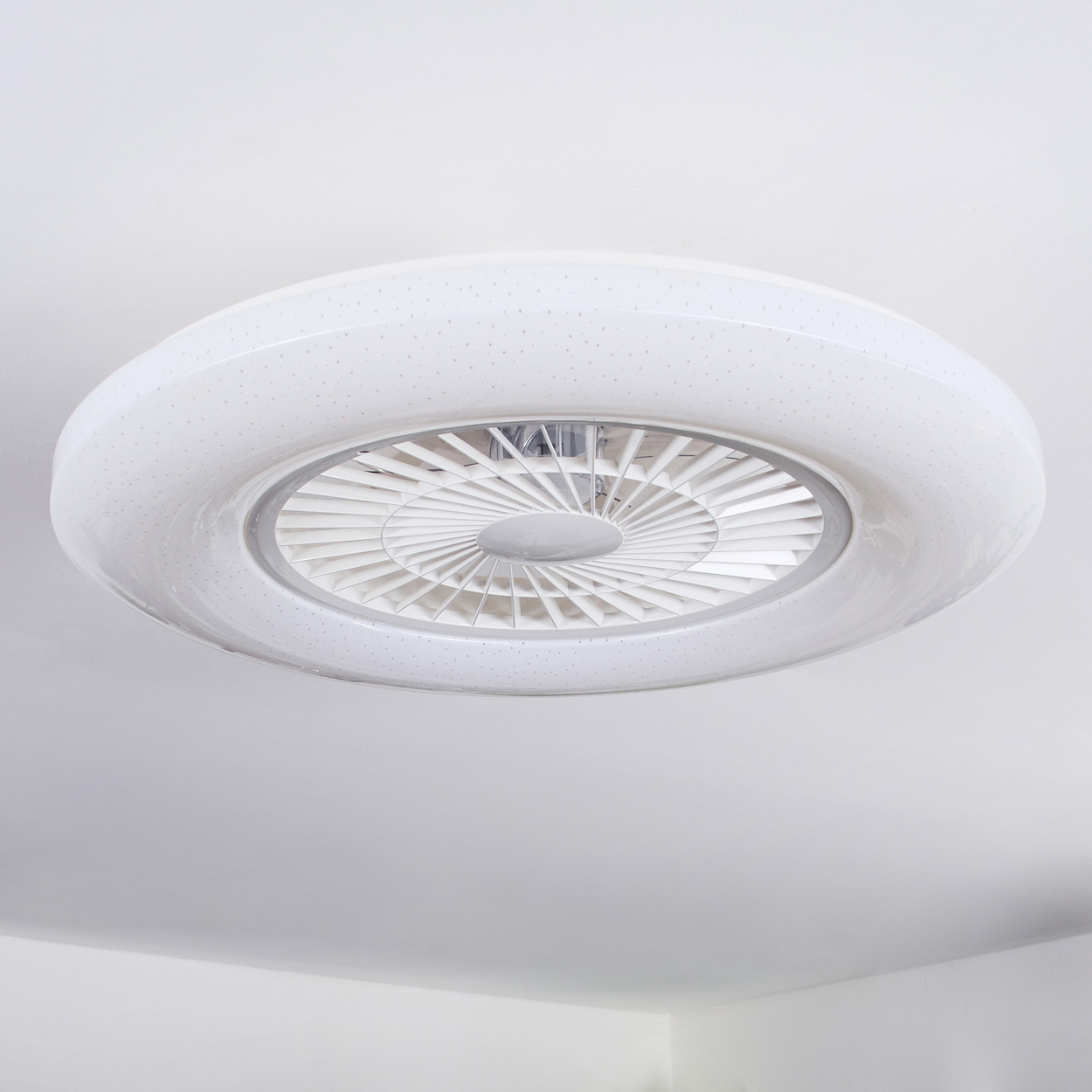 Eine weiße Deckenleuchte mit integriertem Ventilator und Sternenmuster.