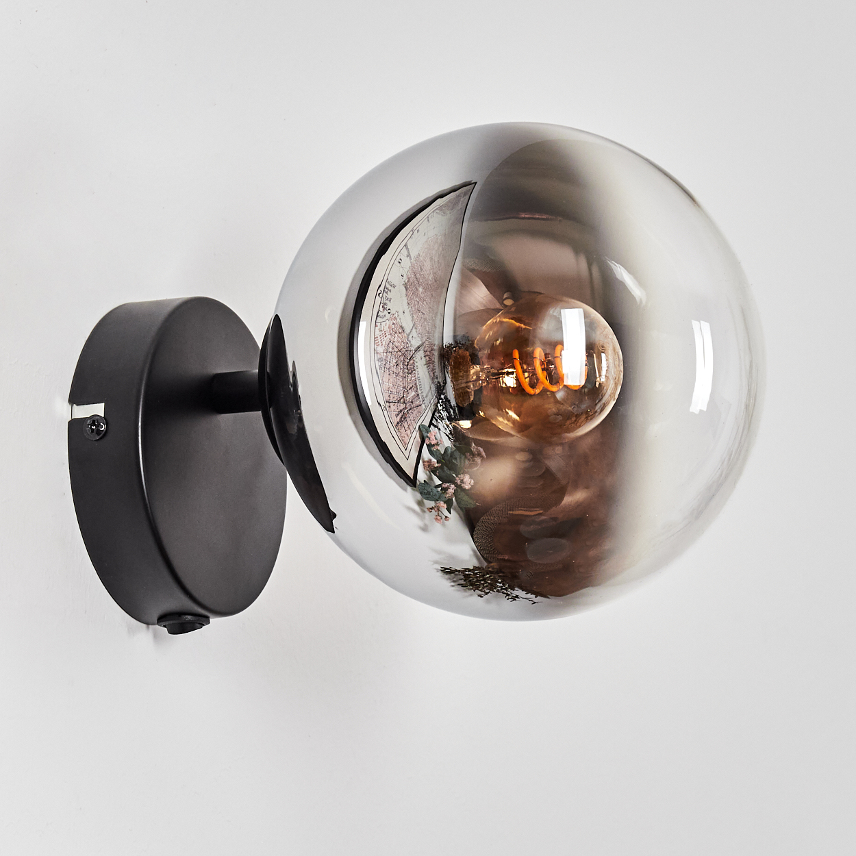 Schwarze Wandleuchte mit kugelförmigem, getöntem Glasschirm, der eine Glühbirne zeigt.