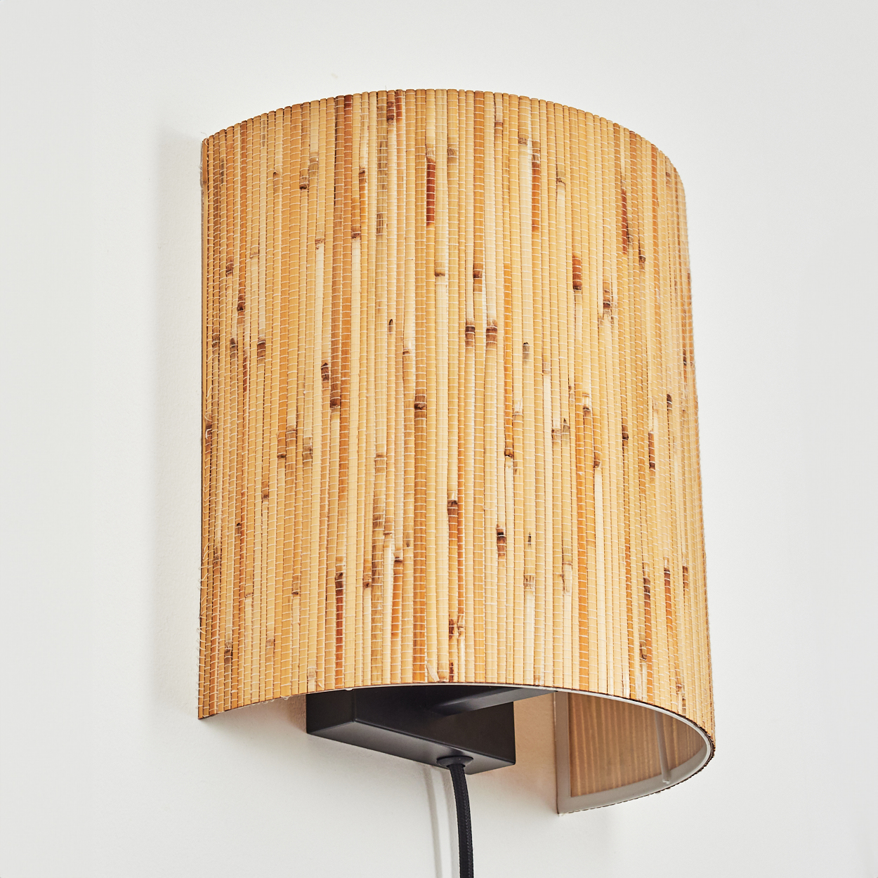 Eine Wandleuchte mit einem Lampenschirm aus natürlichem Rattan auf weißem Hintergrund.