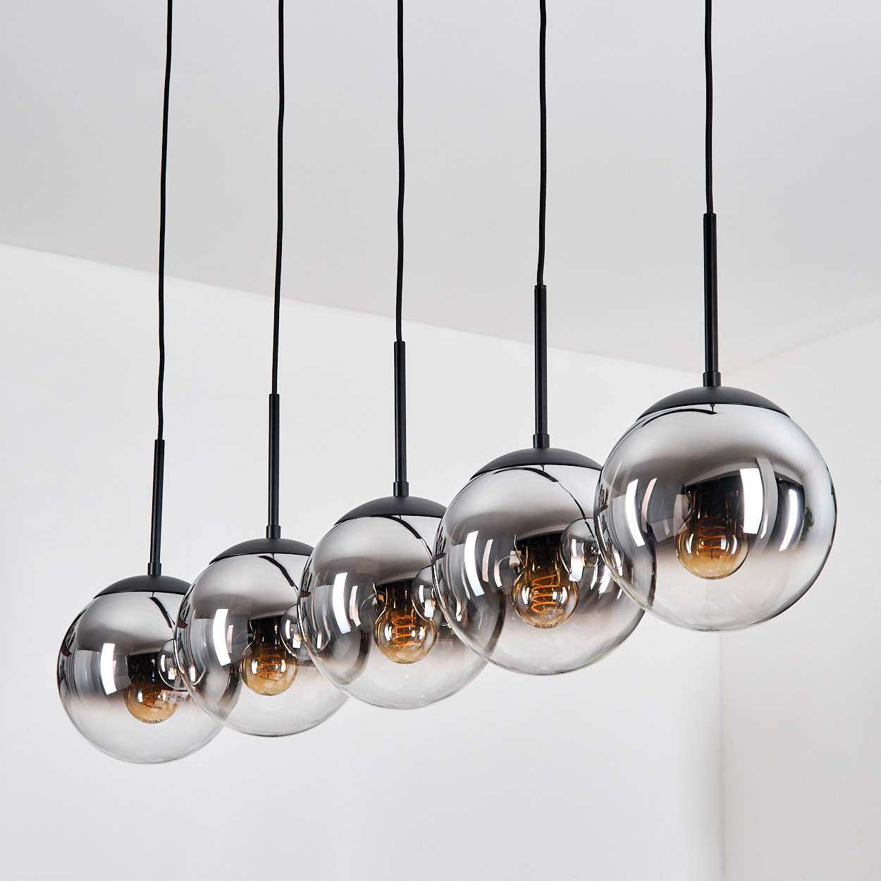 Fünf hängende Lampen mit verspiegelten Glaskugeln und sichtbaren Glühbirnen.