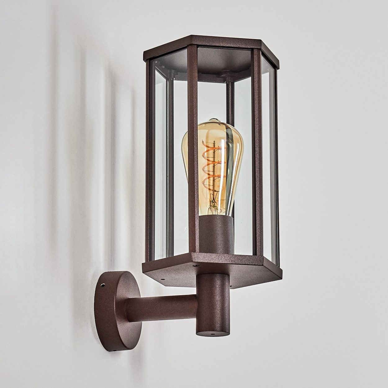 Eine braune Wandleuchte mit einer Edison-Glühbirne und Glasscheiben.