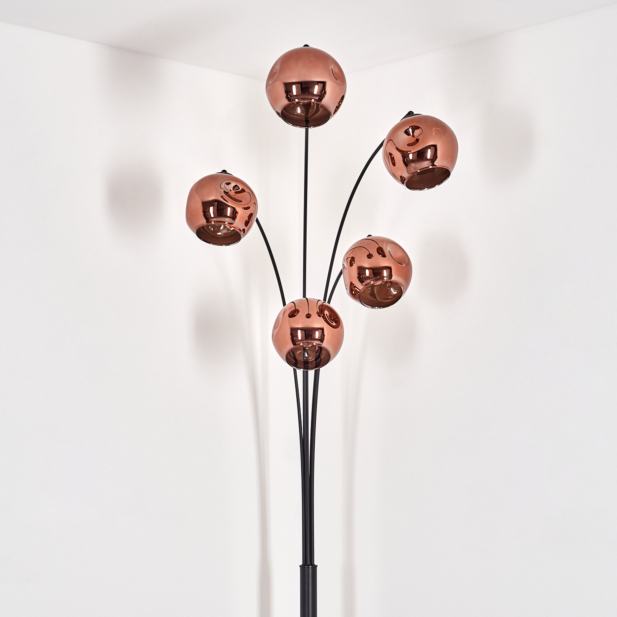 Eine Stehlampe mit fünf kugelförmigen, kupferfarbenen Lampenschirmen an schwarzen Stielen.