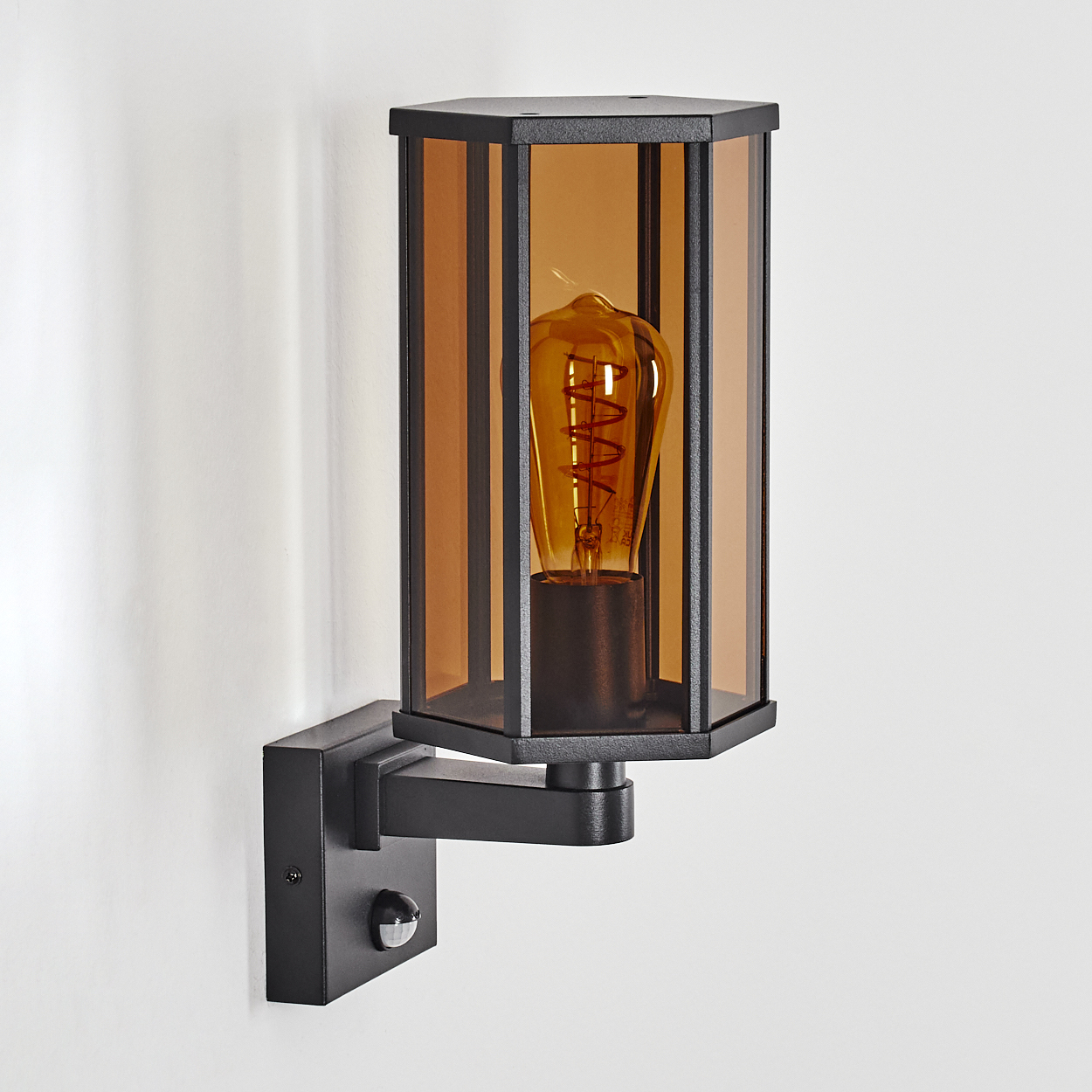 Schwarze Außenwandleuchte mit bernsteinfarbenem Glas und Edison-Birne. Inklusive Bewegungsmelder.