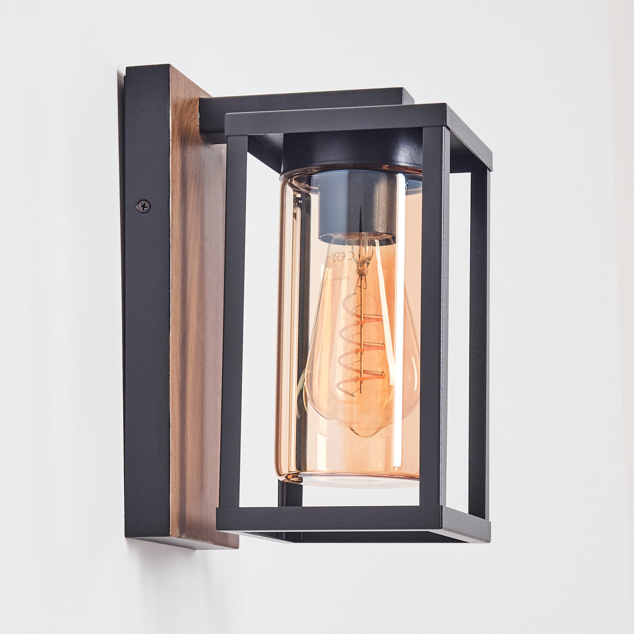 Eine moderne schwarze Wandleuchte aus Metall mit Holzrückwand und einem klaren Glaszylinder mit Edison-Glühbirne.