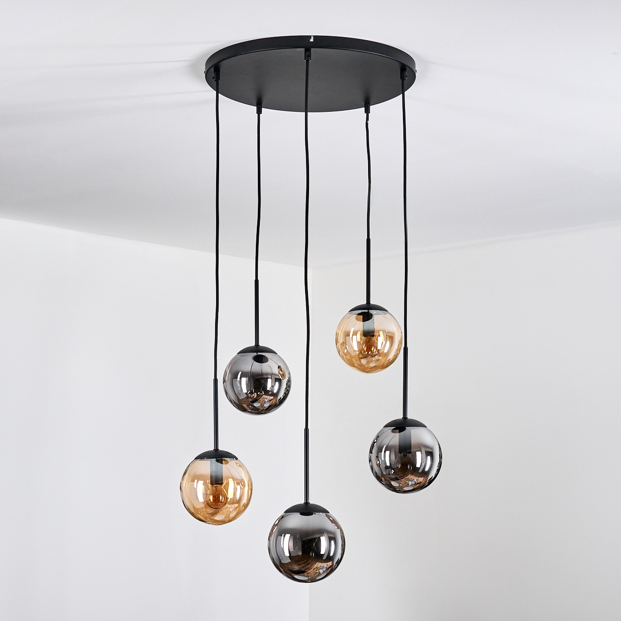 Eine schwarze Deckenleuchte mit fünf hängenden Glaskugeln in Bernstein und Rauchglas.