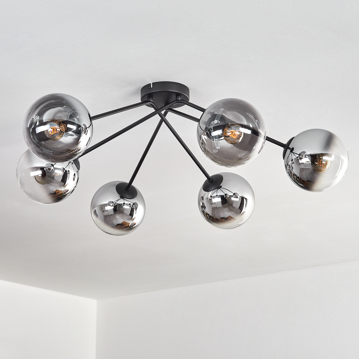 Moderne Deckenleuchte mit sieben Glaskugeln an schwarzen Armen.