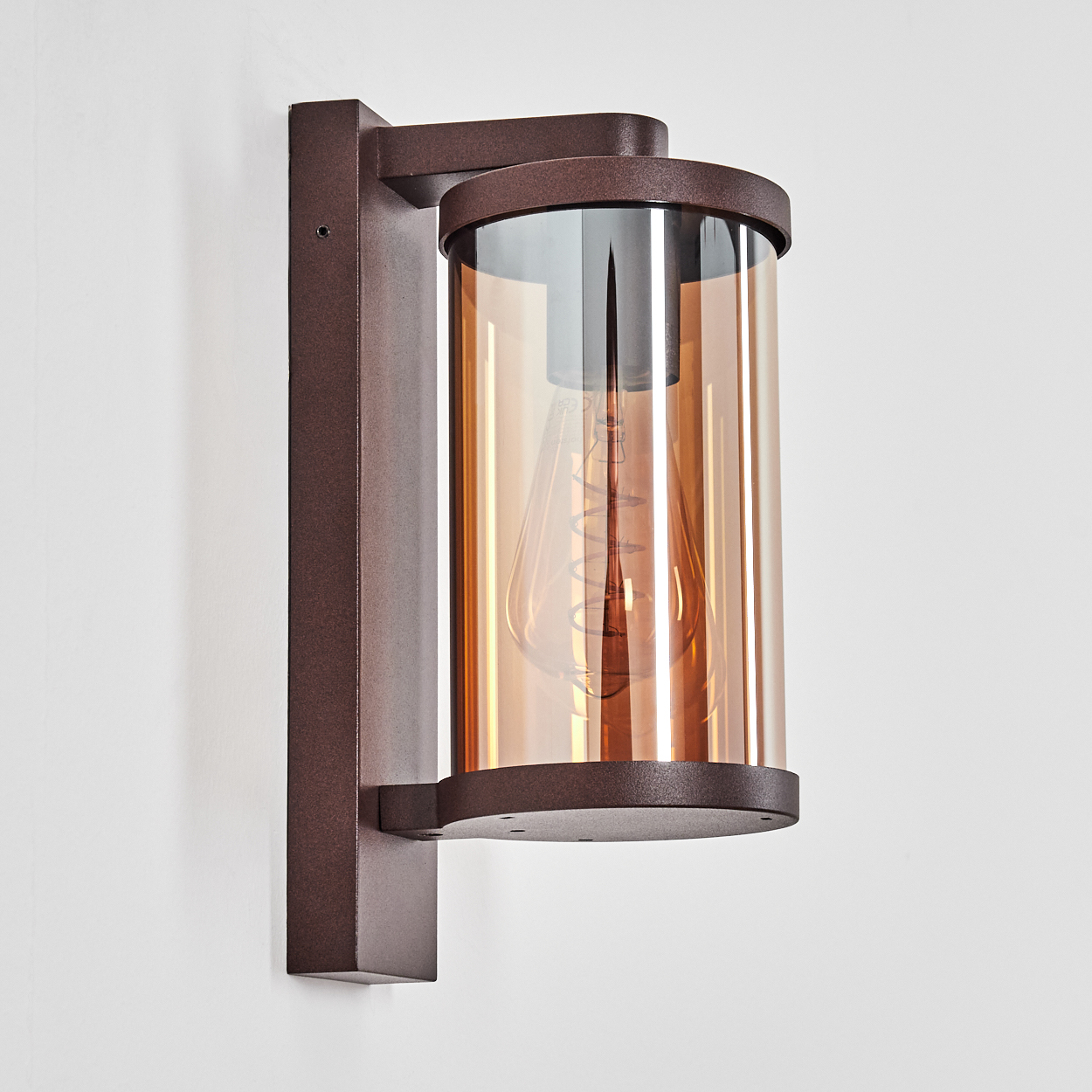 Eine braune Wandleuchte mit zylindrischem Bernstein-Glas und sichtbarer Glühbirne.